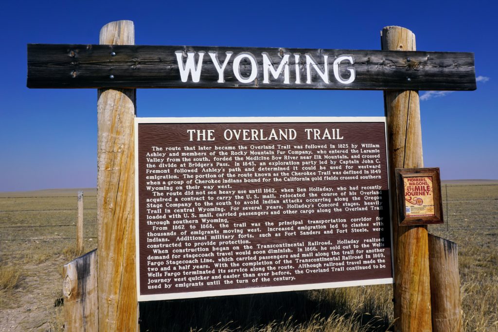 Large wooden historical marker sign titled Wyoming The Overland Trail detailing the path used by 1860s stagecoaches and pioneers through the region.