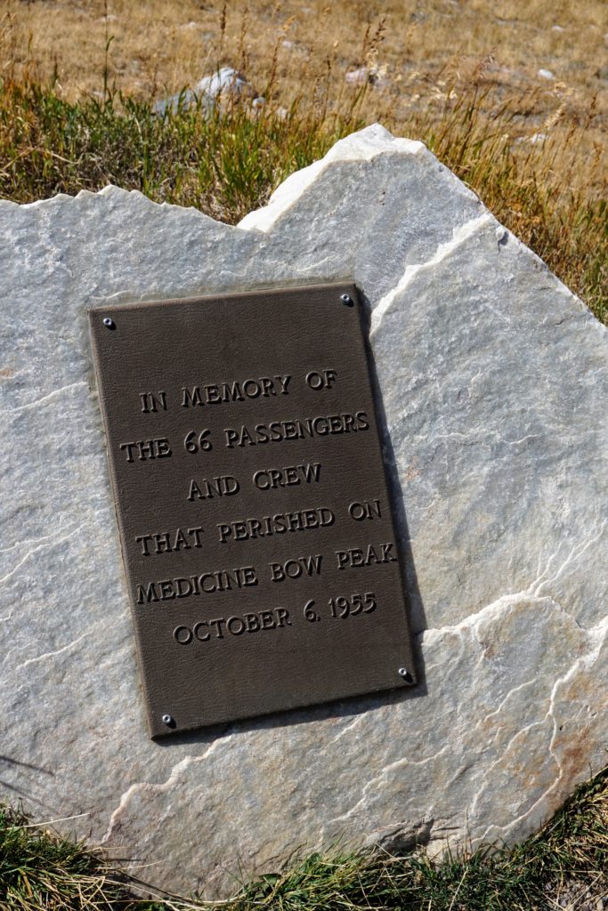 Close-up of a bronze historical memorial plaque mounted on a light-colored quartzite boulder along the Snowy Range trail.