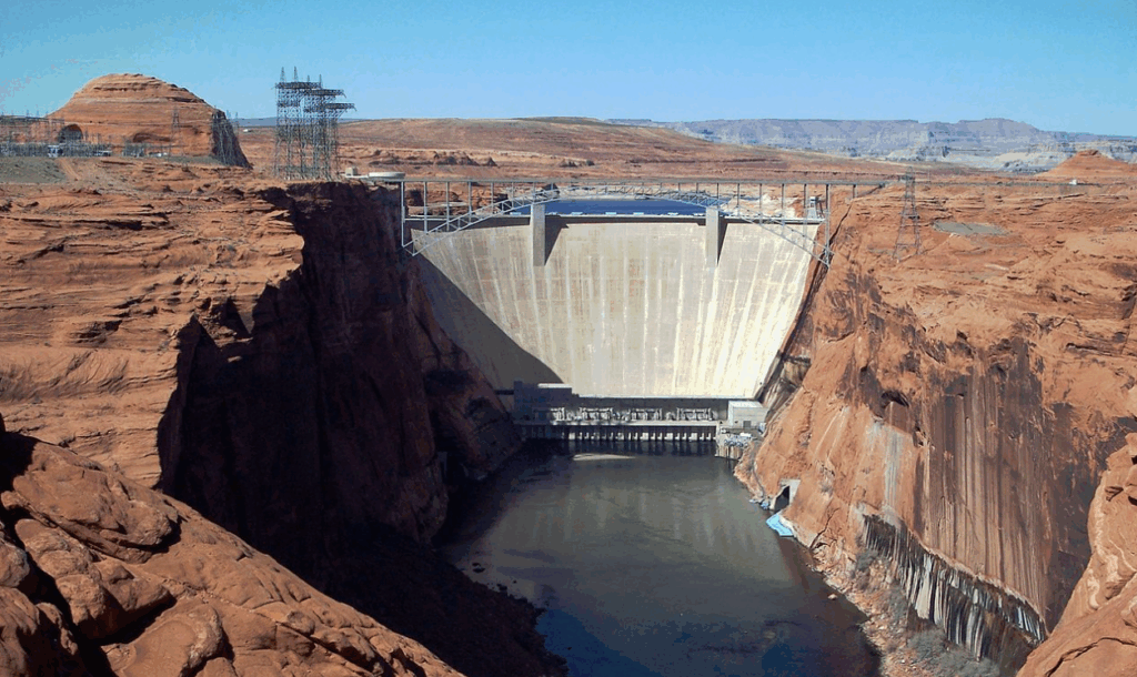 Downriver view of Glen Canyon Dam wall nestled in red sandstone canyon cliffs