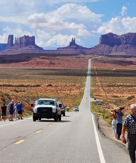 Tourists and vehicles stopped on Highway 163 at Forrest Gump Point overlooking Monument Valley