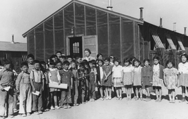 Black-and-white photo of children and adults outside the schoolhouse at Topaz Japanese internment camp, Utah