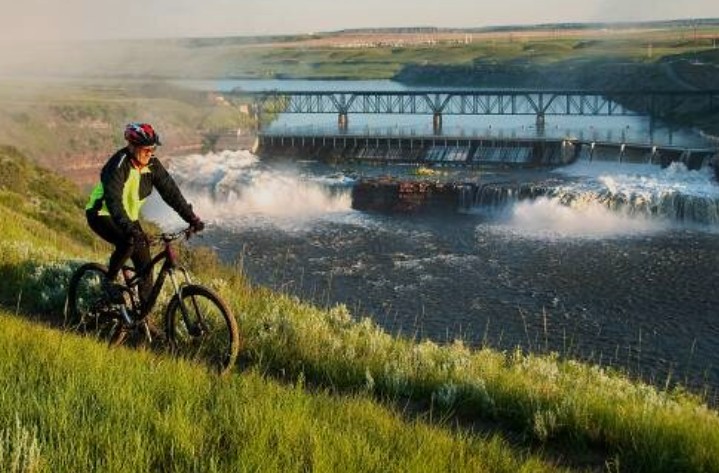 Mountain biker riding the River's Edge Trail past a Missouri River dam in Great Falls Montana