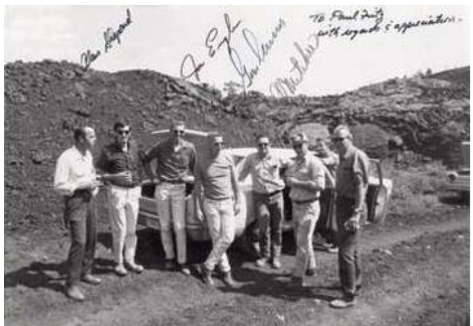 Historical black and white photo of Apollo astronauts Alan Shepard, Joe Engle, Gene Cernan, and Ed Mitchell standing in a rocky Idaho lava field in August 1969.