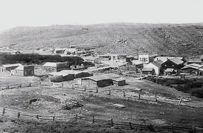 Wide historic black and white landscape view of the buildings and dirt roads in South Pass City Wyoming in 1906