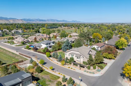Aerial view of modern suburban neighborhoods in Wheat Ridge, Colorado with mountains in the background.