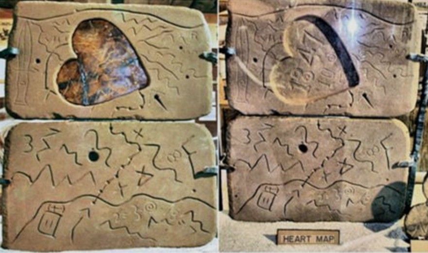 Stone slabs carved with trail maps, symbols, and a heart-shaped cutout.