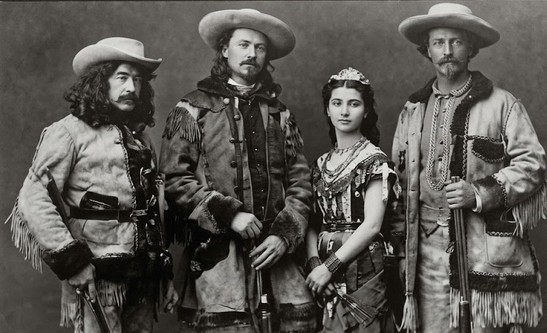Buffalo Bill Cody standing with performers in his Wild West show.