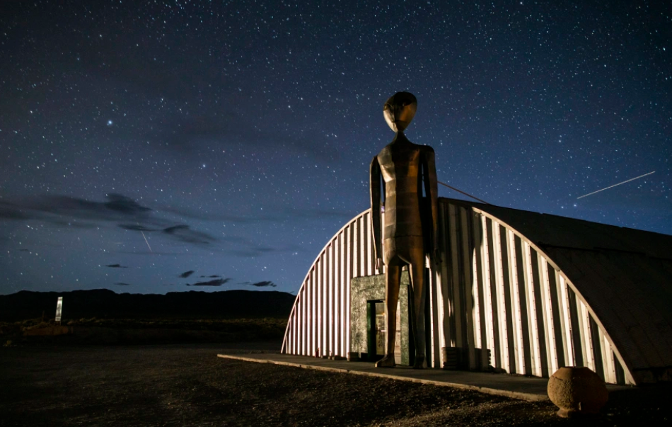Large metal alien statue standing in front of the Alien Research Center along Nevada's Extraterrestrial Highway at night.