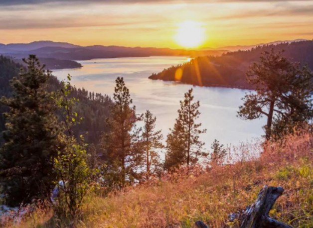 Scenic sunset over a mountain lake and pine forest landscape in northern Idaho.