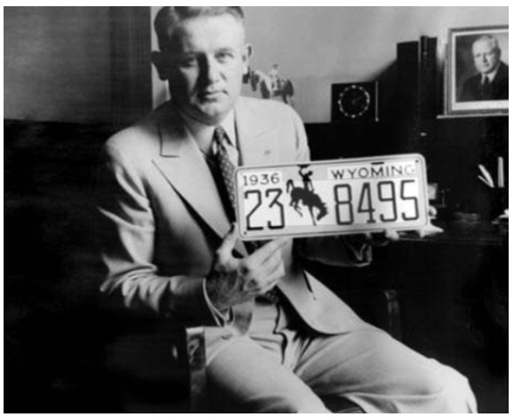 Lester C. Hunt holding the first 1936 Wyoming license plate with the bucking horse logo