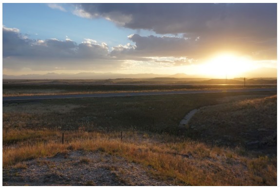 Sunset over the open plains of Wyoming under a cloudy sky.